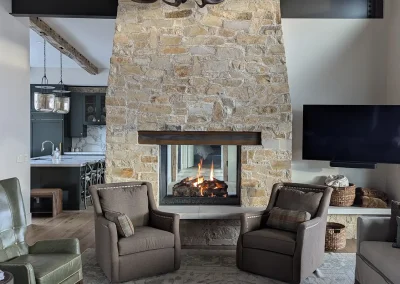 A custom Acucraft fireplace installed by Croft Fireplace, featuring a sleek black metal frame and a large glass enclosure. Vibrant orange and yellow flames dance inside, enhancing the stylish, contemporary interior with warm lighting and a cozy ambiance.