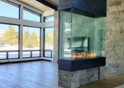 Modern glass corner fireplace in spacious room with large windows