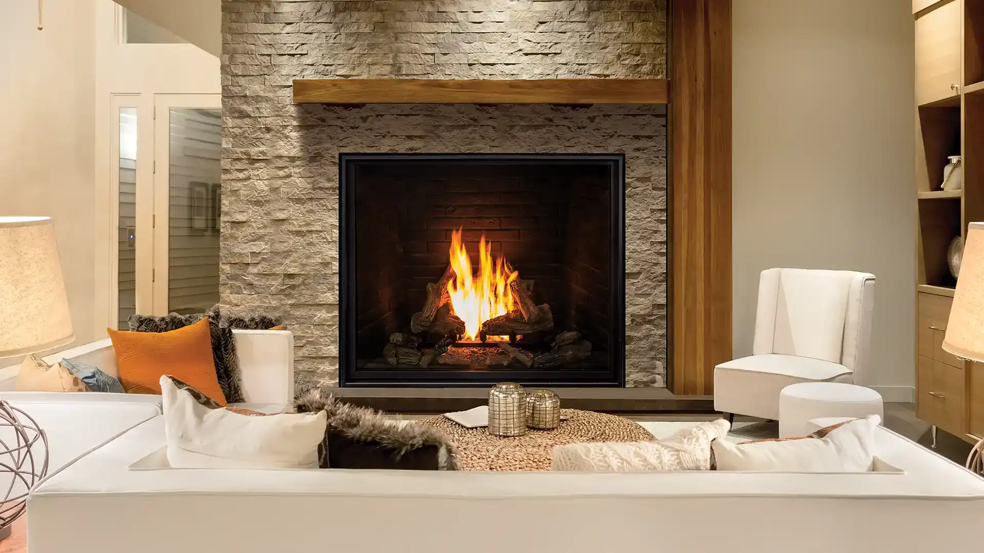 A modern bedroom featuring the Urbana Luxury Fireplace U33Tall see-through, with floor-to-ceiling windows, an ocean view, and cozy, elegant furnishings.