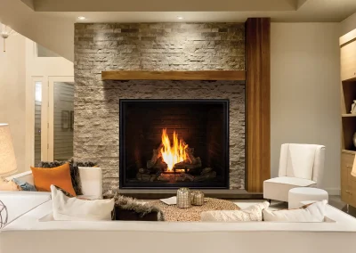 Croft Fireplace stacked-stone gas fireplace with wood mantel in a comfortable, rustic-modern living room